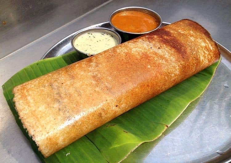 Masala dosa on a banana leaf with coconut and tomato chutney